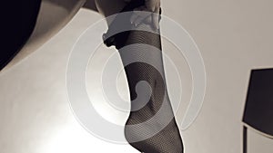 Young woman slowly puts on black net stockings. Incognito. Concept of teasing, foot, nylon fetish, body beauty.