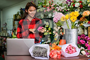 Young woman, small business, florist arranging plants in flower shop