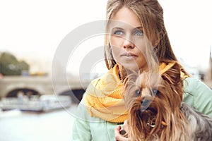 Young woman with small dog on the embarkment, waiting friend.