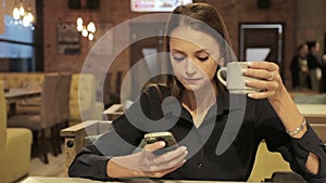Young woman with smartphone drinking coffee in cafe