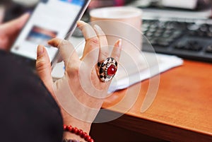 A young woman with a smartphone in hand, keyboard defocuses.