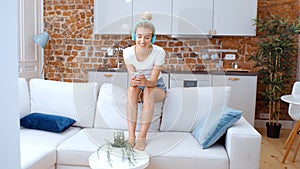 Young woman with smartphone and headphones at home.