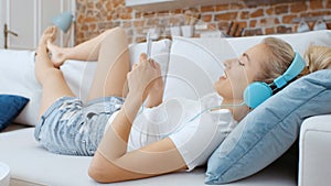 Young woman with smartphone and headphones at home.