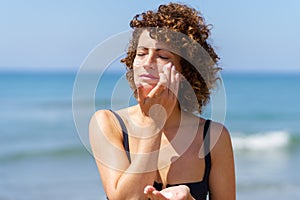 Young woman smearing sunblock cream on face