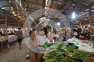Young Woman Smell Herbs Choosing Green Potherbs On Market Girl Shopping On Street Bazaar