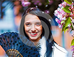 Young woman smelling a beautiful sakura blossom