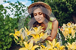 Young woman smelling flowers in garden. Gardener taking care of lilies. Gardening concept