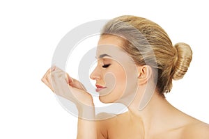 Young woman smelling perfume on her wrist.
