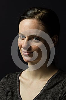 Young woman smiling against black background, horizontal