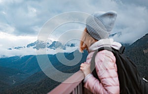 young woman smiling with a backpack in a hat, admiring looks at the mountains.