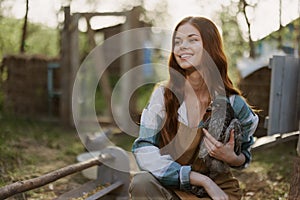 Young woman smiling for the camera holding a chicken and happy working on the farm