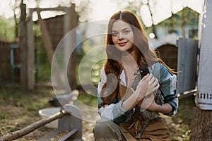 Young woman smiling for the camera holding a chicken and happy working on the farm