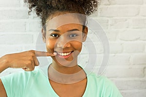 Young woman smiling confidence pointing finger showing teeth white.