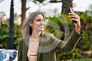 Young woman smiling confident making selfie by the smartphone at park