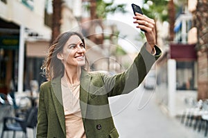 Young woman smiling confident making selfie by the smartphone at street