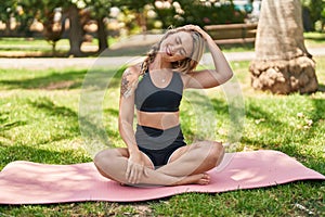 Young woman smiling confident stretching neck at park