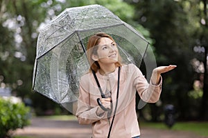 young woman smiling and enjoying under umbrella in rainy season