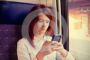 Young woman smiling feeling relaxed and talking to mobile phone traveling near train window