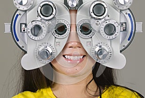 Young woman smiling happy looking through optometric hospital device and checking eyes having sight exam in ophthalmology health