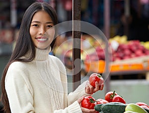 Young woman smiling and holding vegetables at market