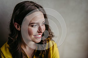 Young woman smiling looking aside studio portrait on gray copy space.
