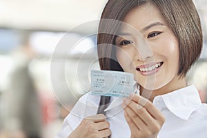 Young Woman Smiling and Looking at a Train Ticket