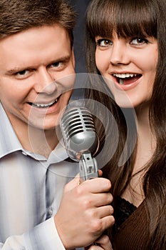 Young woman and smiling man sing in microphone photo