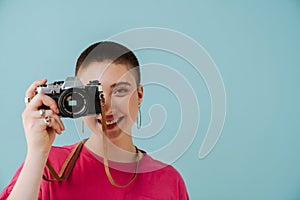 Young woman smiling while posing with retro camera