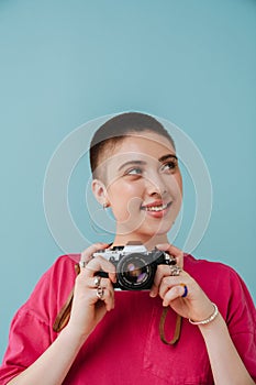 Young woman smiling while posing with retro camera