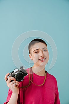 Young woman smiling while posing with retro camera