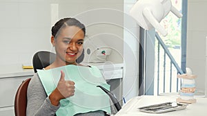 Young woman smiling showing thumbs up waiting for dental checkup