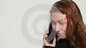 Young woman smiling and talking on her cell phone on a white background. Front view of a young casual woman speaking on