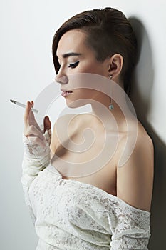 Young woman with smoking cigarette. girl in wedding dress