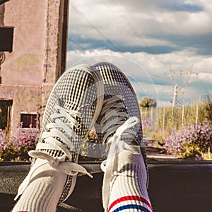 Young woman with sneakers with feet propped on the car window at sunset