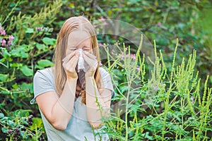 Young woman sneezes because of an allergy to ragweed