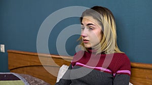 Young woman sneezes. The girl is sick lying on the bed. Closeup