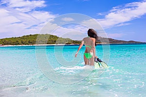 Young woman with snorkeling gear on tropical beach