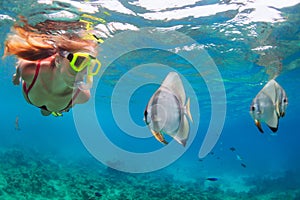 Young woman in snorkeling mask dive underwater with tropical fishes photo