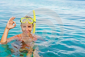 Young woman in snorkeling mask showing divers sign OK