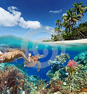 Young woman snorkeling over coral reef in tropical sea.