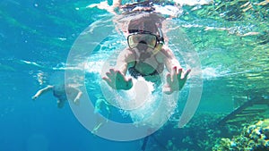 Young woman with snorkelling mask and tube swimming in red sea near coral reef