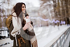 Young woman in a snow park drinks tea