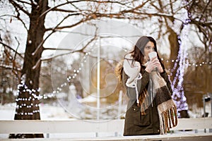 Young woman in a snow park drinks tea