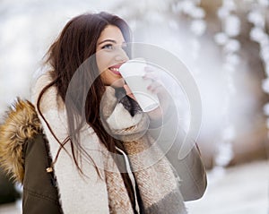 Young woman in a snow park drinks tea