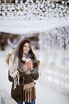 Young woman in a snow park drinks tea