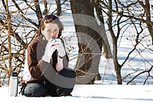 Young woman in snow with thermos bottle