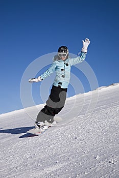 Young woman on snowboard on the slope of mountain
