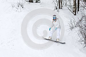 Young woman snowboarder in motion on snowboard in mountains