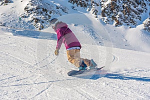 Young woman snowboarder in motion on snowboard in mountains