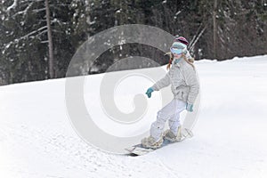 Young woman snowboarder in motion on snowboard in mountains